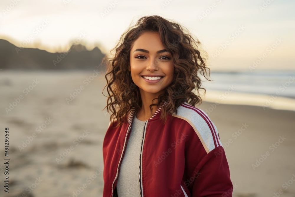 Portrait of a smiling indian woman in her 20s sporting a stylish varsity jacket in sandy beach background Portrait of a smiling indian woman in her 20s sporting a stylish varsity jacket in sandy beach background