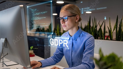 A photo of a woman in a data analytics role. She is wearing glasses and is programming on a computer. There is a hologram of code above the woman's head. The background is a modern office with plants.