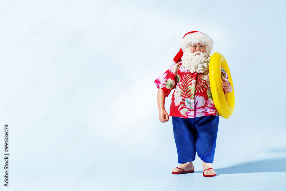 Obraz premium Santa Claus with inflatable ring over blue background. Christmas tropical vacation.
