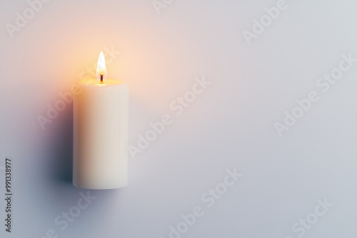 A single lit candle glows softly on a white background, casting gentle shadows, symbolizing remembrance, hope, and prayers for the faithful departed on All Souls' Day.