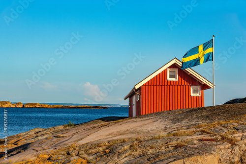 Rotes Schwedenhaus mit Schwedischer Falgge an der Küste am Meer