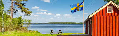 Rotes Schwedenhaus mit Schwedischer Falgge an der Küste am Meer