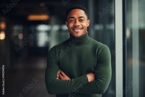 Portrait of a cheerful man in his 20s wearing a classic turtleneck sweater isolated on sophisticated corporate office background