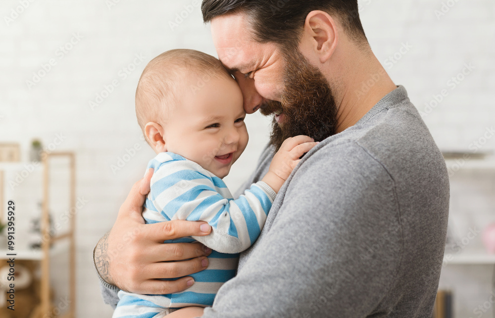 Cheerful father and son cuddling at home, enjoying time together Cheerful father and son cuddling at home, enjoying time together