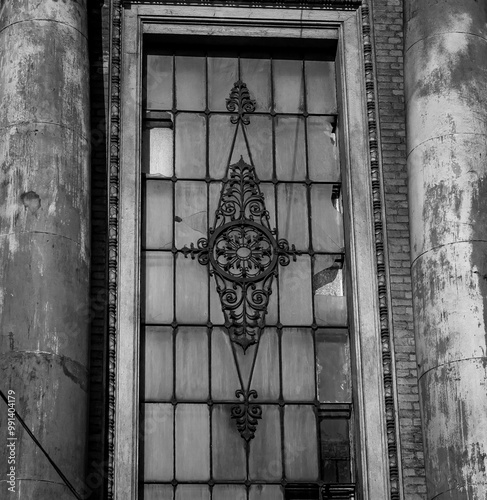 Urban architecture, vintage pattern on window of building with architectural cracked facade. Black and white vertical photo, building facade. photo