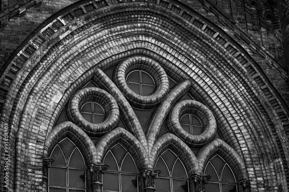 Architectural details, stonework and detailed patterning on an old Gothic church. Black and white horizontal photo from bottom to top.