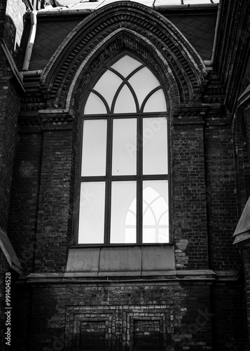 Building cityscape, gothic church architecture, with arched glass windows, christian religion and culture. Black and white vertical photo from bottom to top.