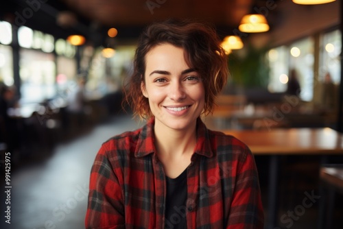 Portrait of a grinning woman in her 30s dressed in a relaxed flannel shirt on bustling restaurant background