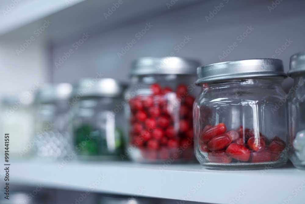 glass jars with candies tablets or beads inside. jars with bright circles on the shelf are arranged in a row. High quality photo glass jars with candies tablets or beads inside. jars with bright circles on the shelf are arranged in a row. High quality photo
