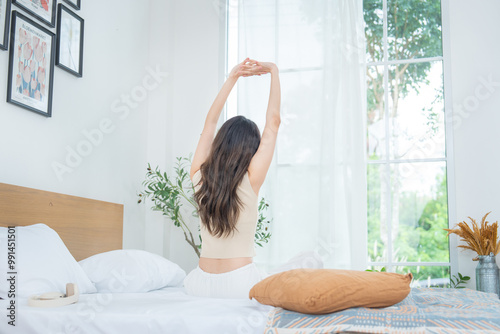 Tableau sur toile Back of young beautiful Asian woman wake up and stretch oneself on bed in the morning with happiness