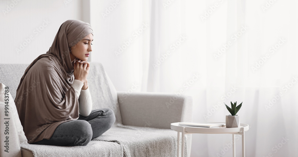 Lonely muslim woman in hijab sitting upset on sofa at home with ...