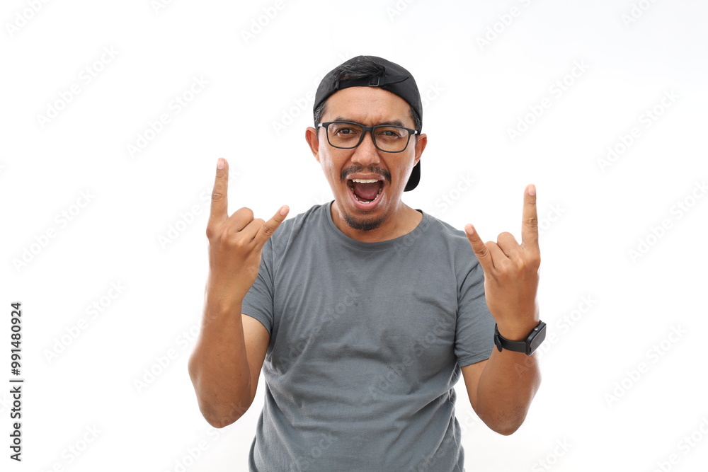 Asian man with beard wearing casual t-shirt and glasses over white background shouting with crazy expression doing rock symbol with hands up. Music star. Heavy music concept. Asian man with beard wearing casual t-shirt and glasses over white background shouting with crazy expression doing rock symbol with hands up. Music star. Heavy music concept.