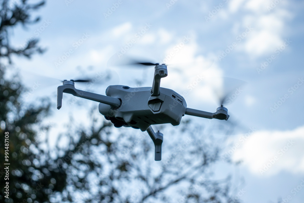 A close-up of a drone flying outdoors on a bright day. The background shows trees and a clear blue sky, creating a sense of outdoor technology in nature. A close-up of a drone flying outdoors on a bright day. The background shows trees and a clear blue sky, creating a sense of outdoor technology in nature.