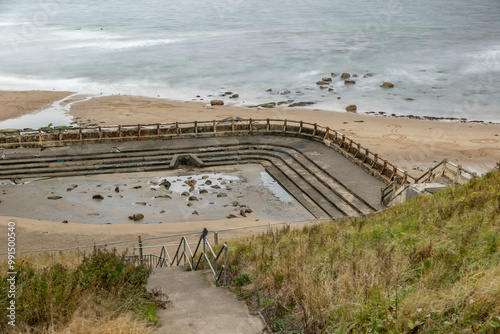 Derelict forlorn ruin of outdoor swimming pool at sea water ocean of bygone glory days of long ago near Newcastle, England, UK