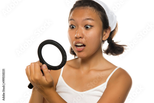 Shocked young asian woman looking her nails with a magnifing glass. photo