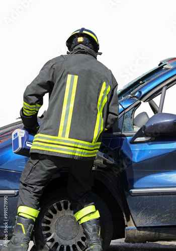 firefighter is using hydraulic shears also known as the Jaws of Life to tear through the sheet metal of a crashed car photo