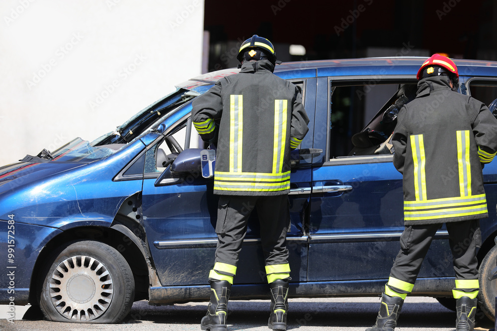 Fototapeta premium Firefighters use hydraulic shears known as Jaws of Life to tear away sheet metal from a crashed car and free a person