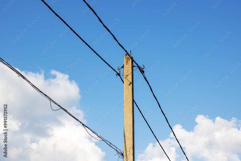 A tall telephone pole stands against a vast blue sky backdrop A tall telephone pole stands against a vast blue sky backdrop