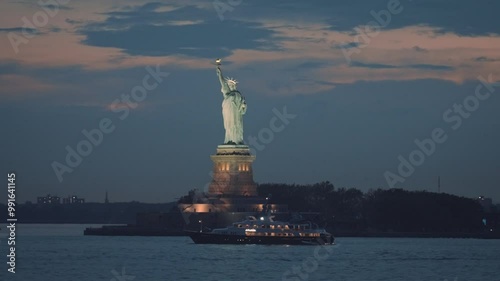 The view of the Statue of Liberty and boats from the New York harbor at dusk. Majestic statue and national symbol in the NYC. Visiting USA. 