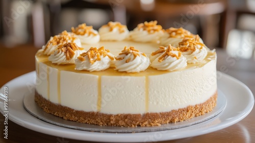 Close up of a round cheesecake with a graham cracker crust and drizzled caramel on a white plate.