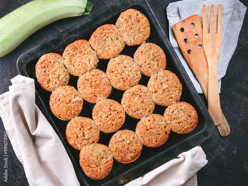 Top view of baking tray with homemade vegetables muffins. Cupkace with zucchini, carrots, apple and cinnamon on black cement background. Sweet vegetables homemade muffins. Toddler-friendly recipe idea photo