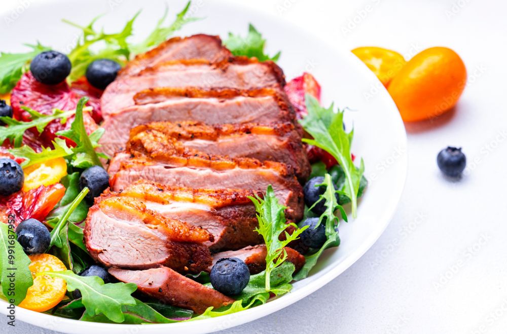 Foodie food salad with baked duck fillet, bloody oranges, kumquat, blueberries and mixed greens, white background, top view