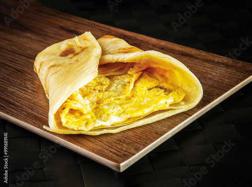 Egg Omelette Paratha Roll shawarma wrap isolated on wooden board closeup side view of oman fastfood photo