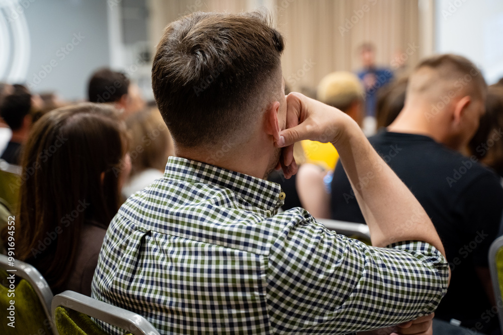 Fototapeta premium An engaged audience actively participating in a dynamic discussion during a conference, showcasing attentiveness and collaboration in their career