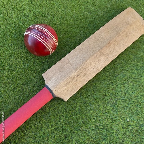 A closeup picture of a cricket bat and ball on a green grass field