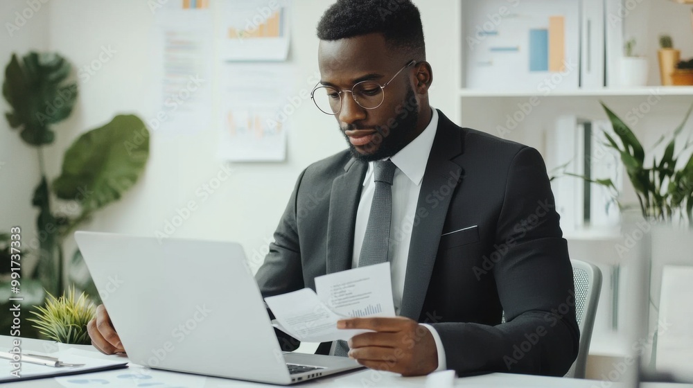 Marketer or analityc manager team dressed in suits working with paper charts and laptops at the white office interior Marketer or analityc manager team dressed in suits working with paper charts and laptops at the white office interior
