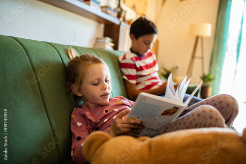 Kids reading books on the couch at home