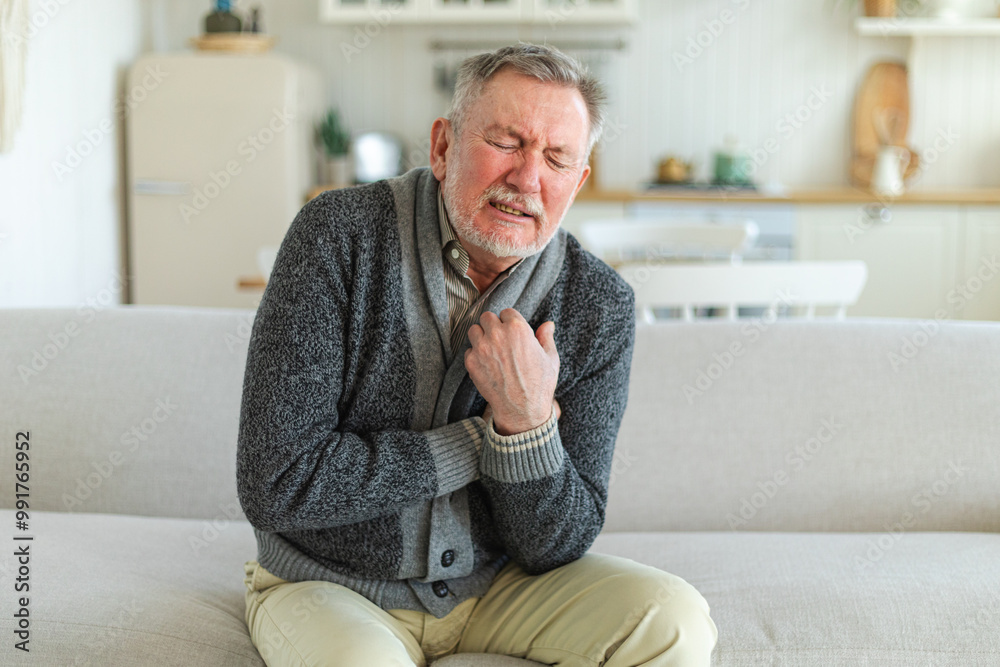 Fototapeta premium Pain on heart, heart attack. Unhappy middle aged senior man suffering from chest pain heart attack problems with health at home. Mature old senior grandfather touching chest experiencing infarction