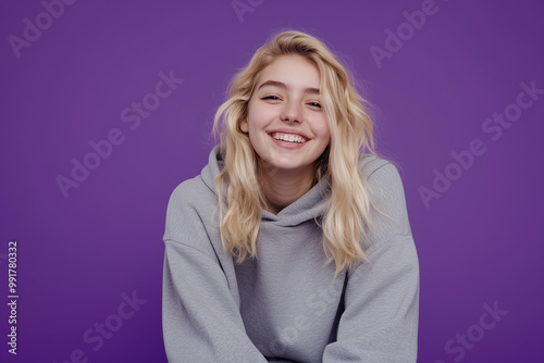 Student in hoodie and sweatpants against purple background with confident smile