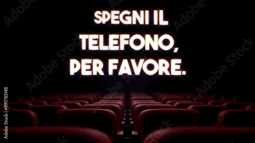 Glowing text SPEGNI IL TELEFONO, PER FAVORE (in Italian: please turn off your phone) appears and dissolves over dark theater interior with rows of empty red velvet seats.
 photo