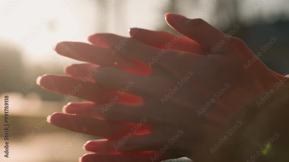 Close-up shot of hands rubbing together in a gesture of deep thought or contemplation. The warm light creates a soft, introspective atmosphere, emphasizing the emotional depth and focus of the moment