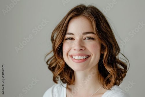 Dark brown haired woman on a white background, glowing skin and smooth hairstyle.