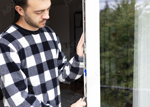 a man standing near the glass door and looking on the locker in the frame.
switching windows and doors to autumn-winter mode, insulating an apartment. seasonal cold snap