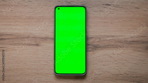 top view of a phone with a green screen on a wooden table
