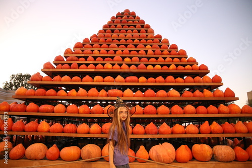 10 years girl in witch hat with pumpkin pyramid in background