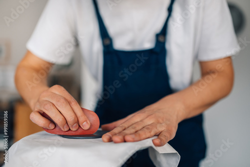 Close up of pottery designer's hands flattening wet clay surface.