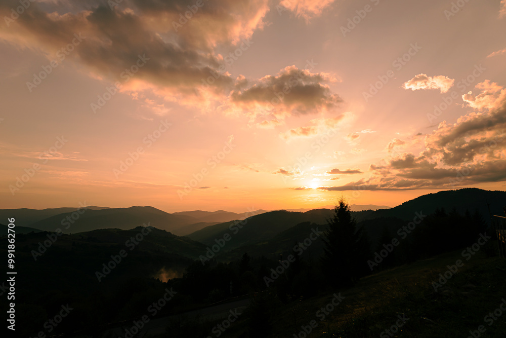 Obraz premium Orange sunset with the setting sun behind the mountains