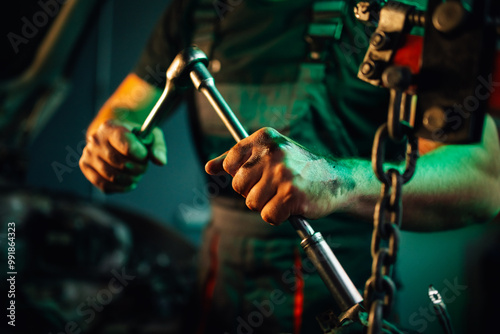 Mechanic tightening a bolt on an engine part with a ratchet wrench.