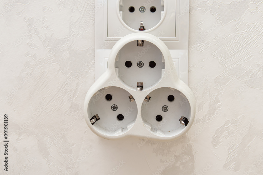 Electric tee for wall outlet on white wall background Electric tee for wall outlet on white wall background