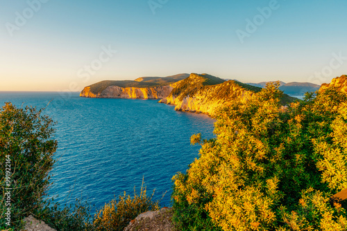 Lighthouse on the cliff. Seascape of Cape Lefkatas with old lighthouse on Lefkada island, Greece. Beautiful views of azure sea water and nature with cliffs photo