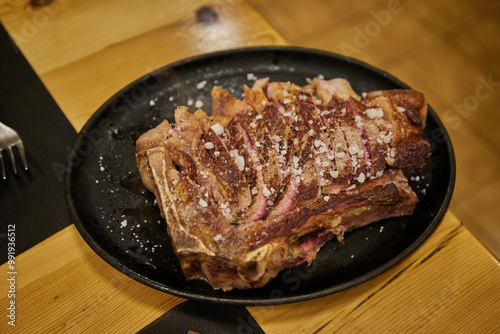 Traditional Spanish rib eye steak on the bone Chuleton, cooked over charcoal and sliced to share, served in a restaurant photo