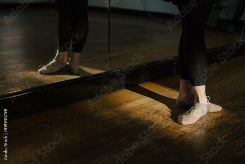 Close-up of ballerina's legs in pink pointe shoes standing in fifth position during ballet class