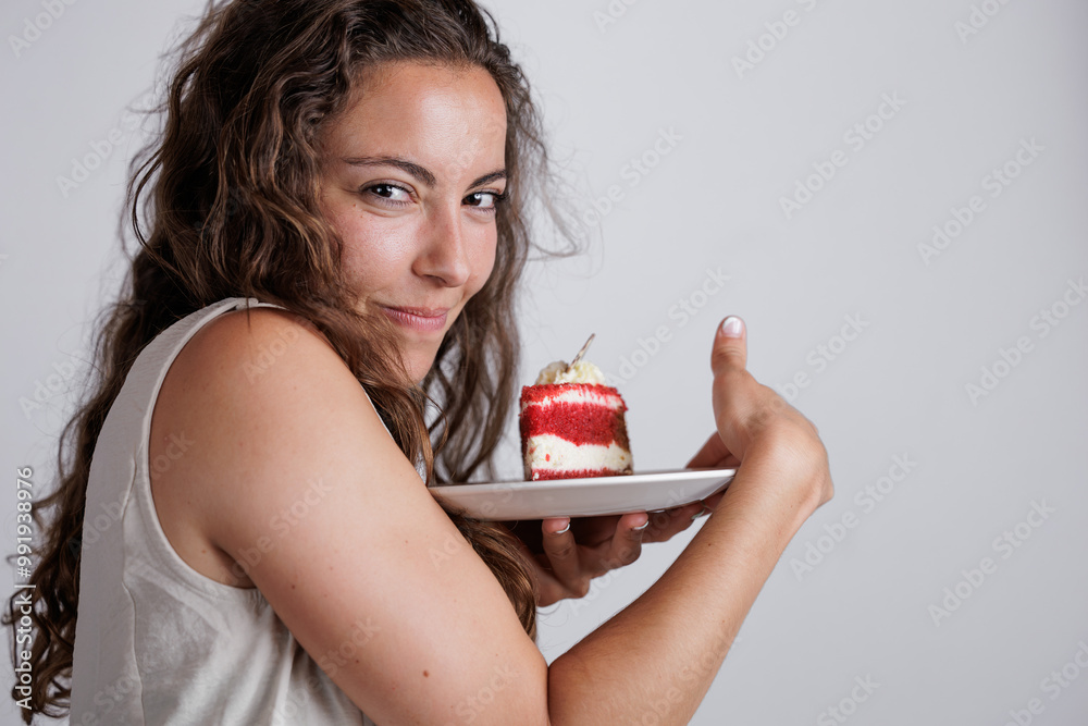 Hungry young woman eating a red velvet cake. Enjoying her celebration. Sugar rush. Sugar cravings. Fun moments eating cake, scooping the cream with fingers. Finger-licking good. Hungry young woman eating a red velvet cake. Enjoying her celebration. Sugar rush. Sugar cravings. Fun moments eating cake, scooping the cream with fingers. Finger-licking good.