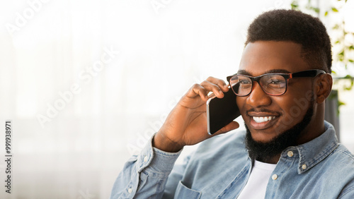 In touch. Handsome african american man in glasses talking on cellphone with somebody, copy space