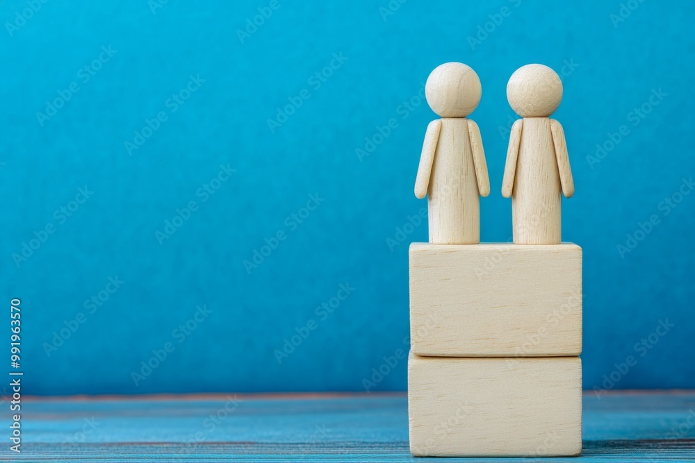 Two wooden figures stand on different blocks in a harmonious arrangement against a blue background Two wooden figures stand on different blocks in a harmonious arrangement against a blue background