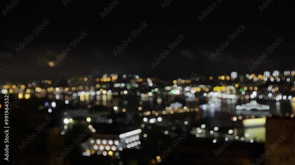 Bokeh blurred twinkling night city lights from buildings near bay water
